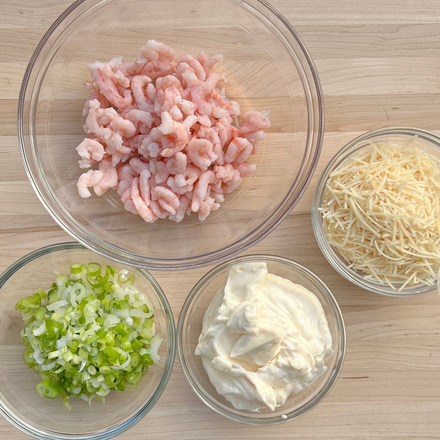 Wild oregon shrimp in a bowl with parm cheese, green onions and may in small bowls on top of a cutting board