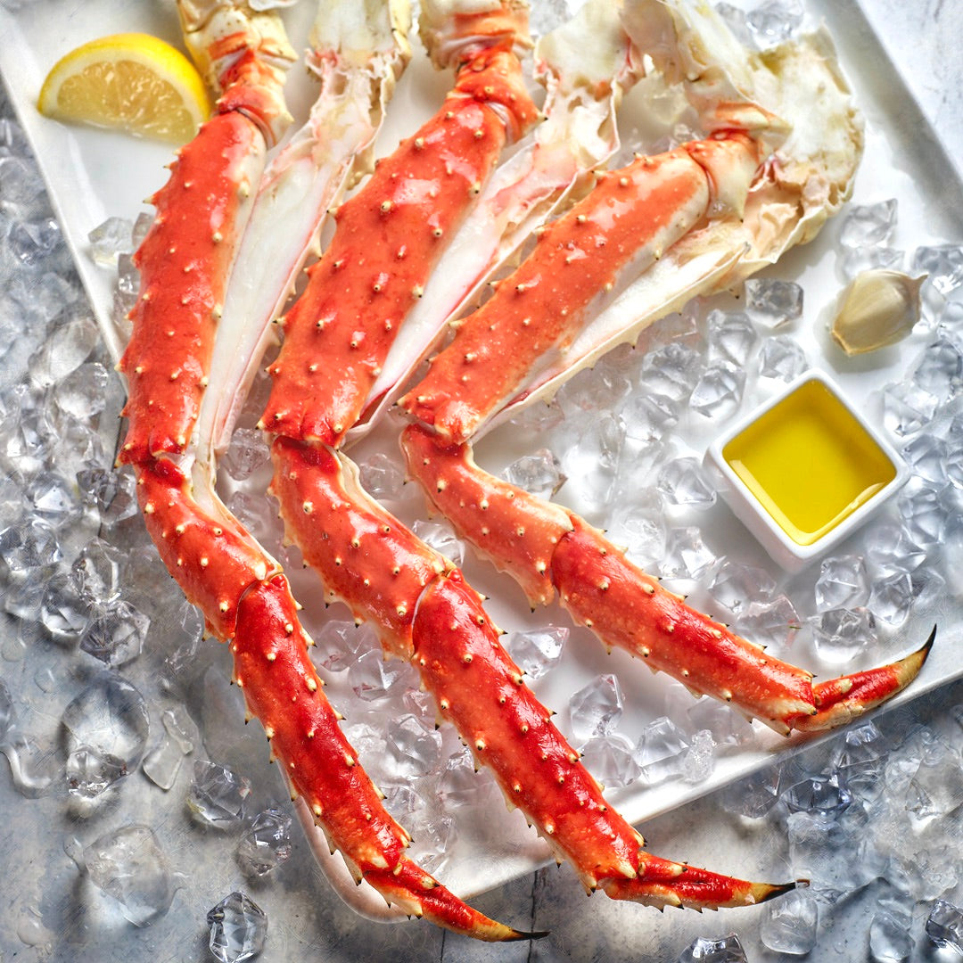 Butterfly split wild Alaskan red king crab legs on ice with lemon and olive oil