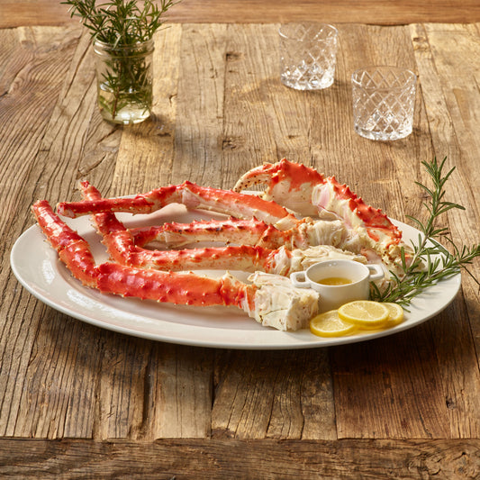 Butterfly split wild Alaskan red king crab legs served on a platter with lemon and melted butter