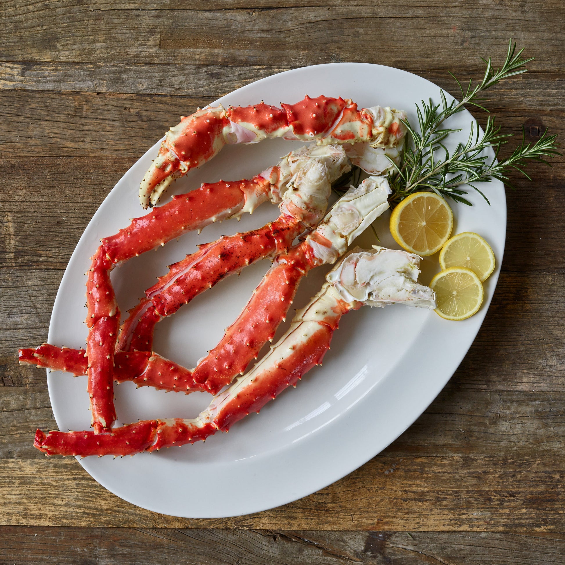 Butterfly split wild Alaskan red king crab legs served on a white plate with lemon