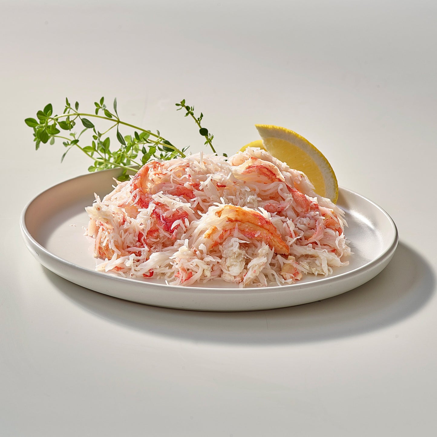 Wild snow crab meat on a plate with lemon wedge and fresh herbs