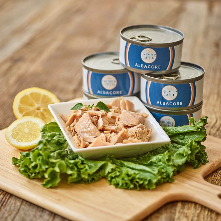 Wild albacore tuna served on crackers with lettuce and lemon beside open cans.