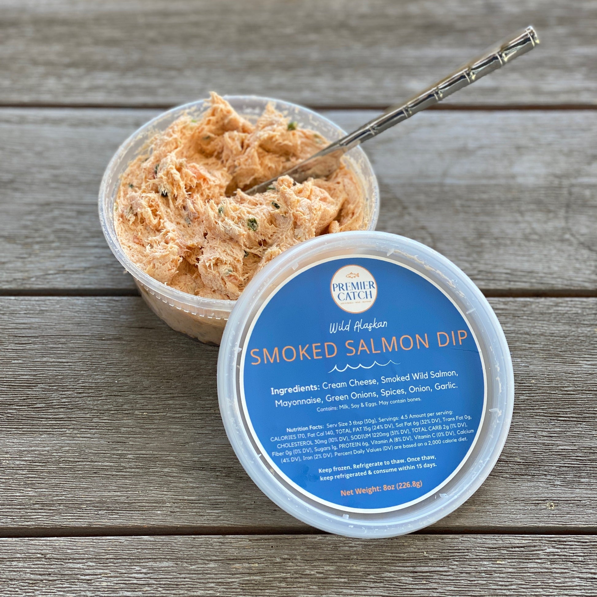 Wild smoked salmon dip in Premier Catch container, open with a knife ready to spread.