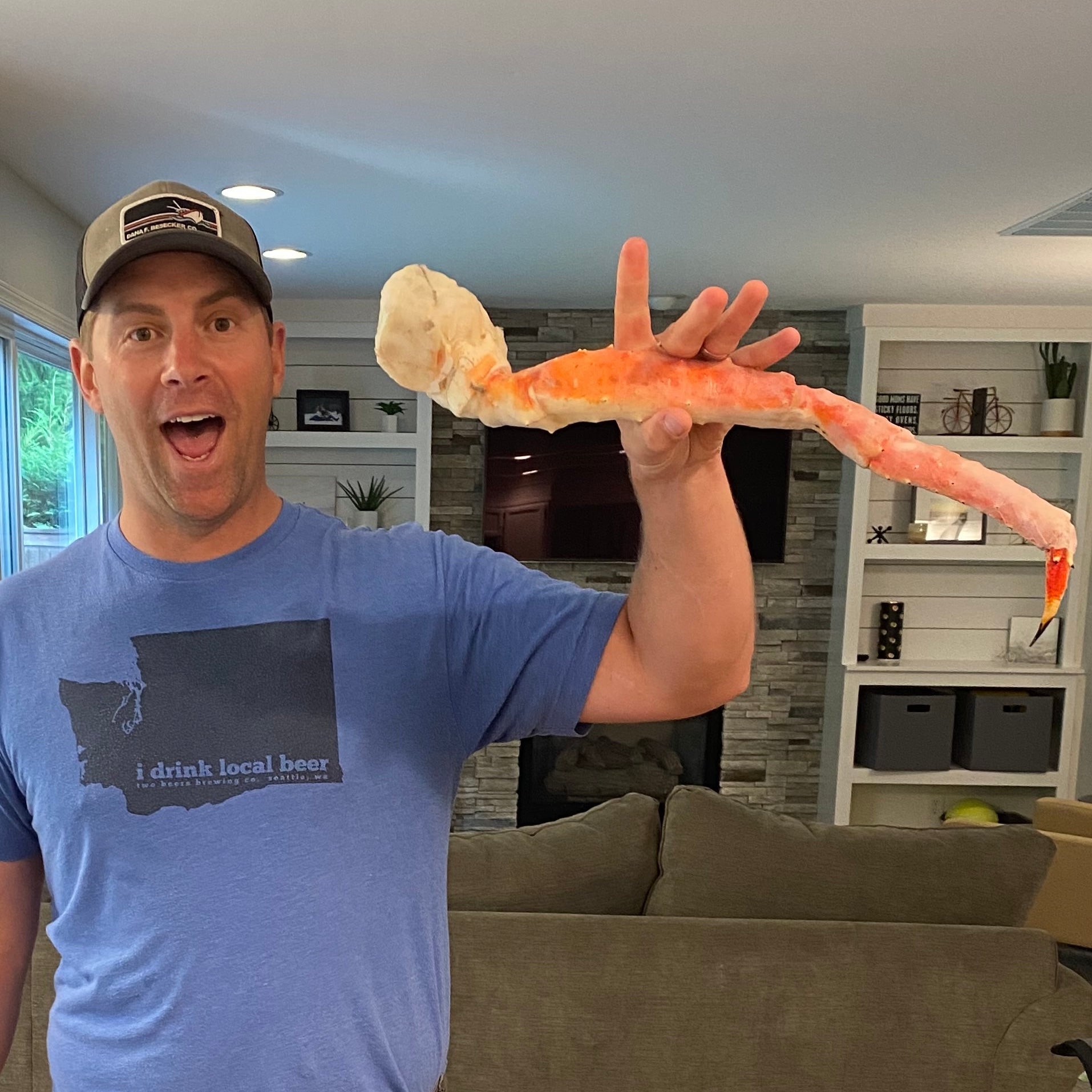 Man holding large butterfly split wild Alaskan red king crab leg for size comparison