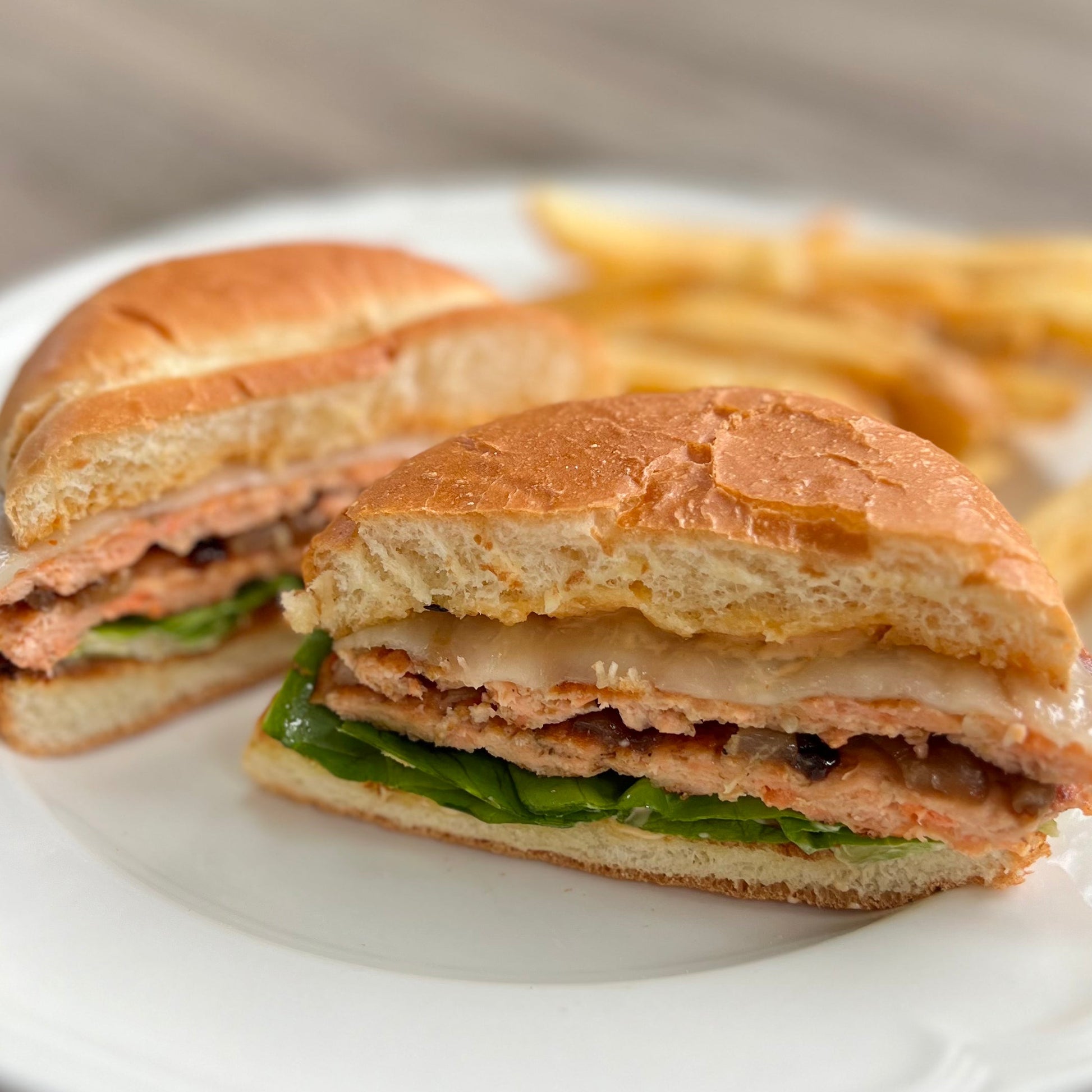Wild salmon smash burgers with lettuce and cheese on a white plate