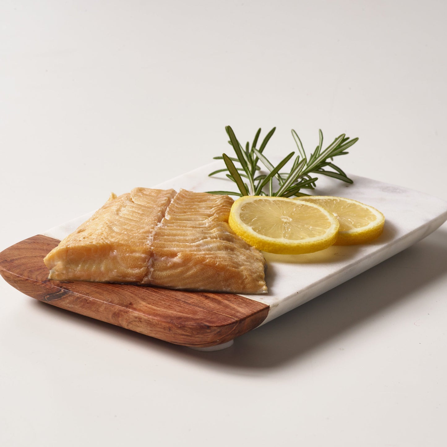 Wild Alaska smoked sablefish served on a wooden board with lemon