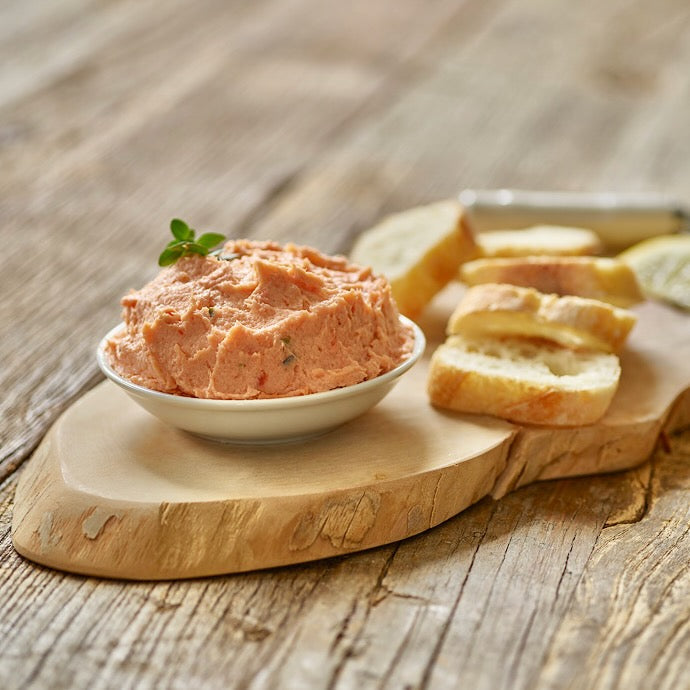 Smoked salmon dip served on a wooden board with crackers, made with wild Alaskan salmon.