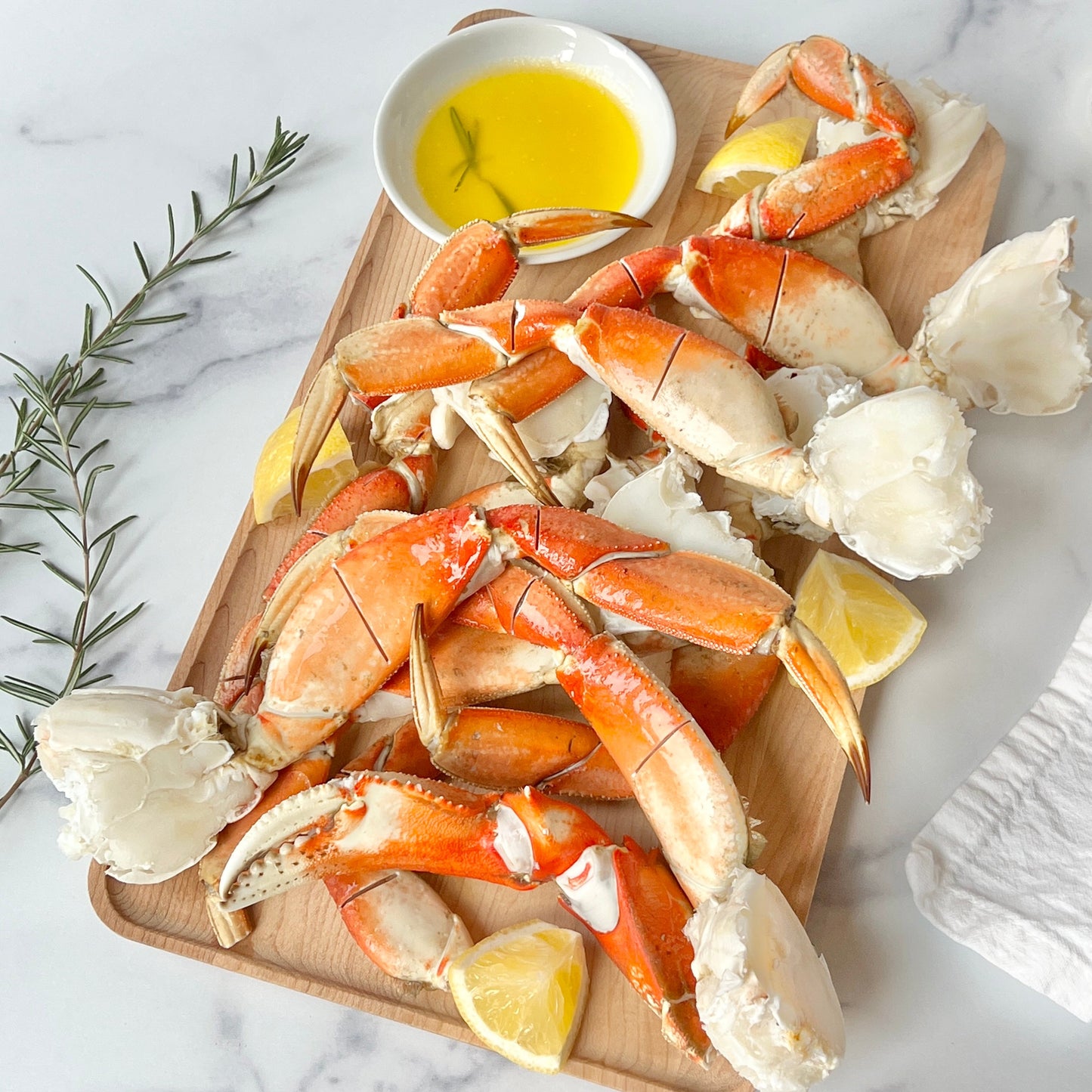 Wild Alaskan Dungeness crab legs on a wooden board with lemon and melted butter