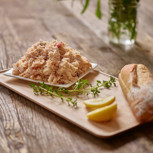 Wild Alaskan Dungeness crab meat served on a wooden board with lemon wedges and bread