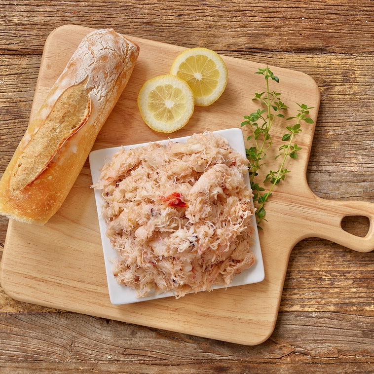 Wild Alaskan Dungeness crab meat on a cutting board with lemon slices and baguette