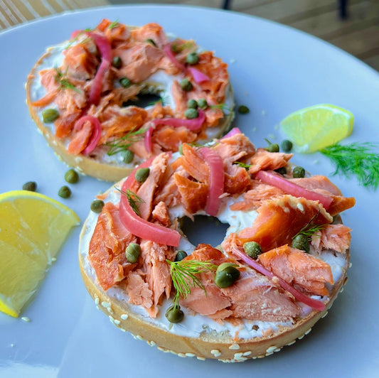 Smoked salmon on top of a toasted bagel with picked onions and cream cheese