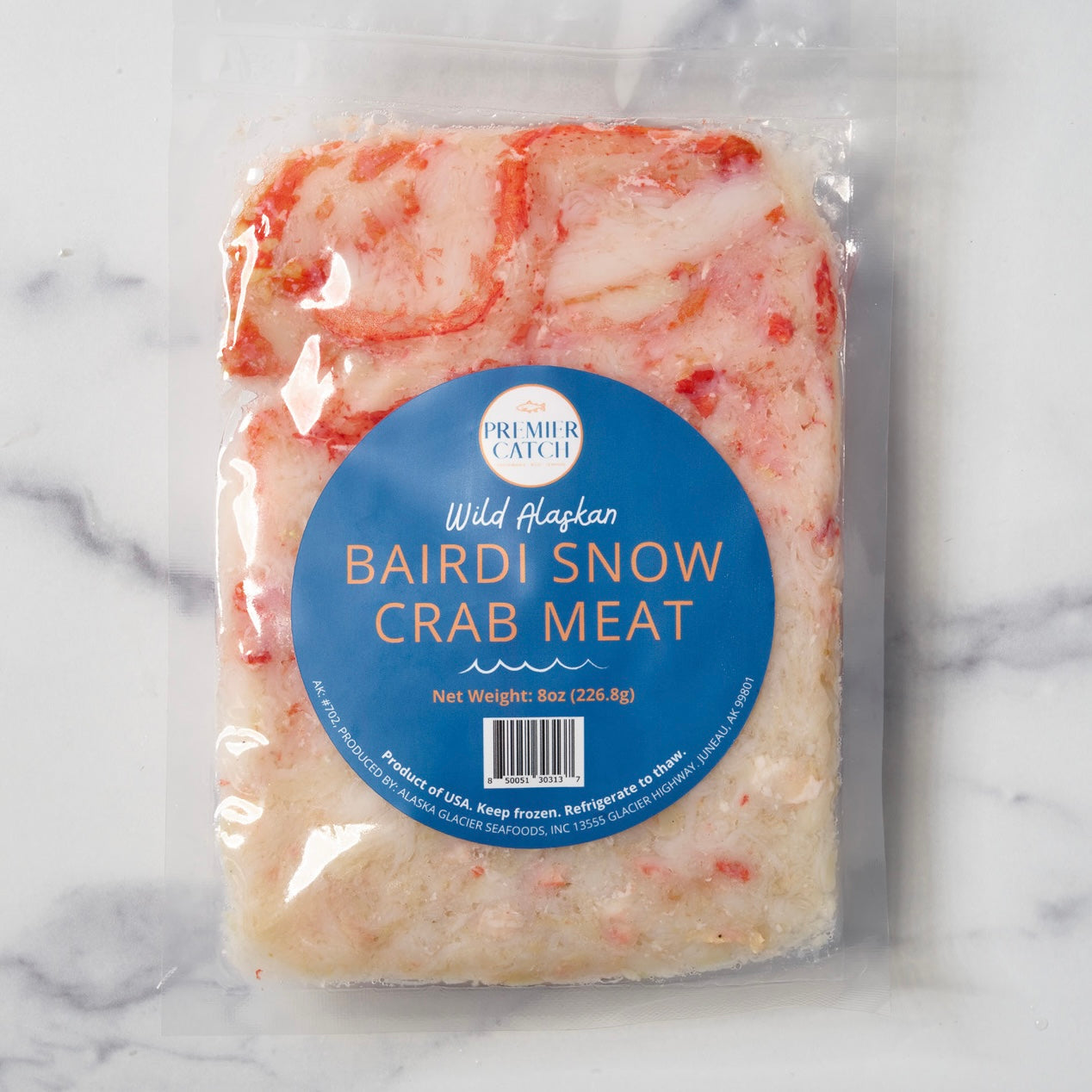 Packaged wild Alaskan Bairdi Snow Crab Meat on a marble background