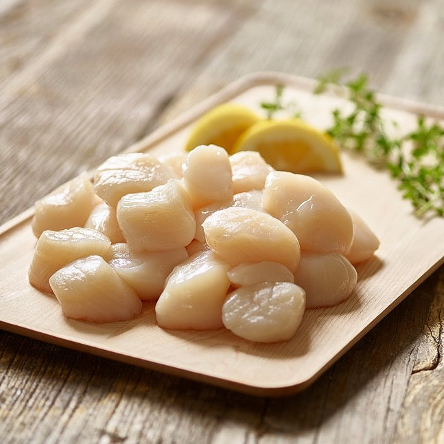Wild Alaska weathervane scallops on a wooden board with lemon wedges