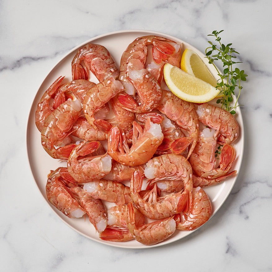 Wild Alaskan spot prawns served on a plate with lemon wedges