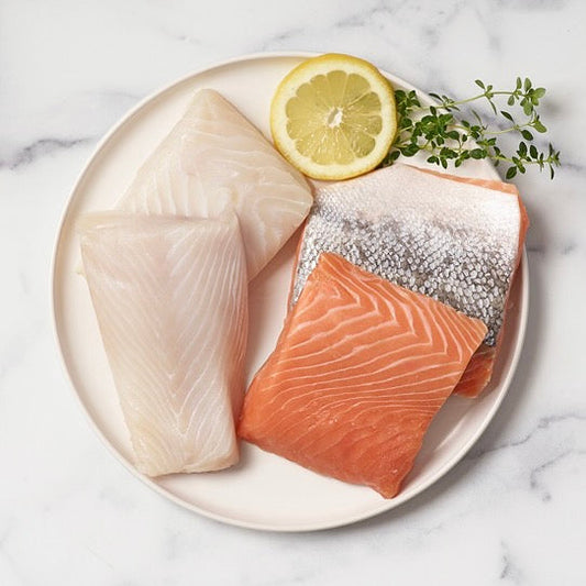 king salmon and halibut on a white plate with a lemon slice