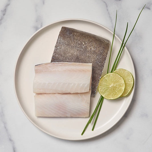 Wild sablefish fillets on a plate with lime slices and chives